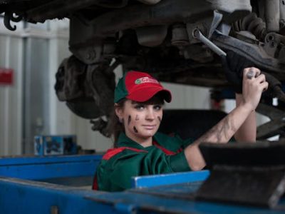 Female mechanic maintaining a car in an auto repair shop, showcasing skill and concentration.