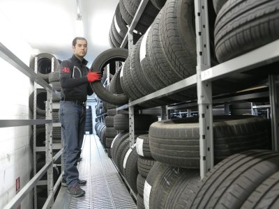 Mechanic places a tire on a rack in an indoor warehouse storage facility.