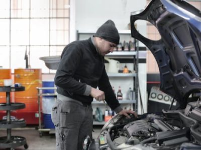 Mechanic checking a car engine in a garage, ensuring quality maintenance and repair.